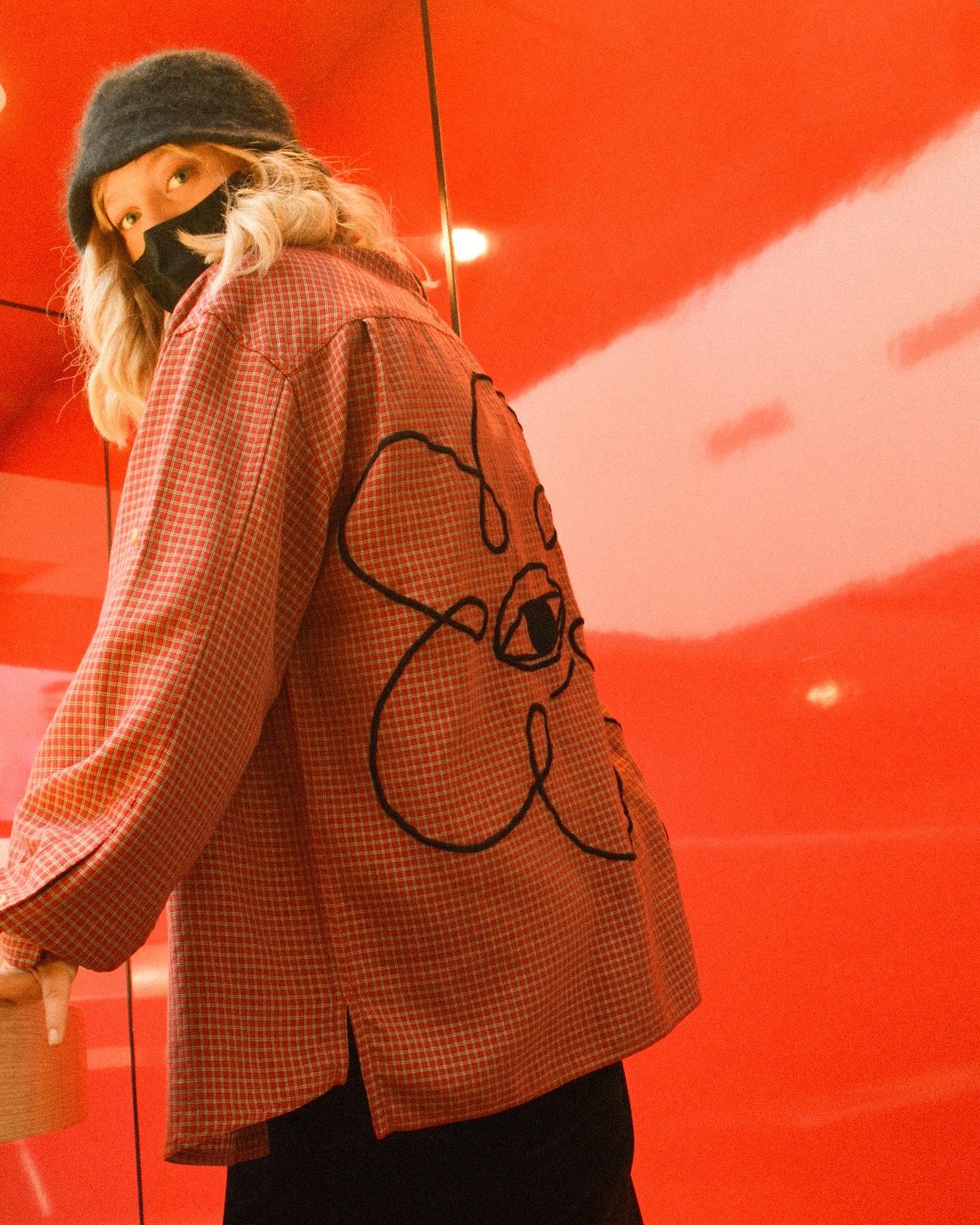 Chemise rouge à motif de fleur ayant un œil brodé à la main par l’artiste Caroline Auger. Drummondville, Québec. 2021