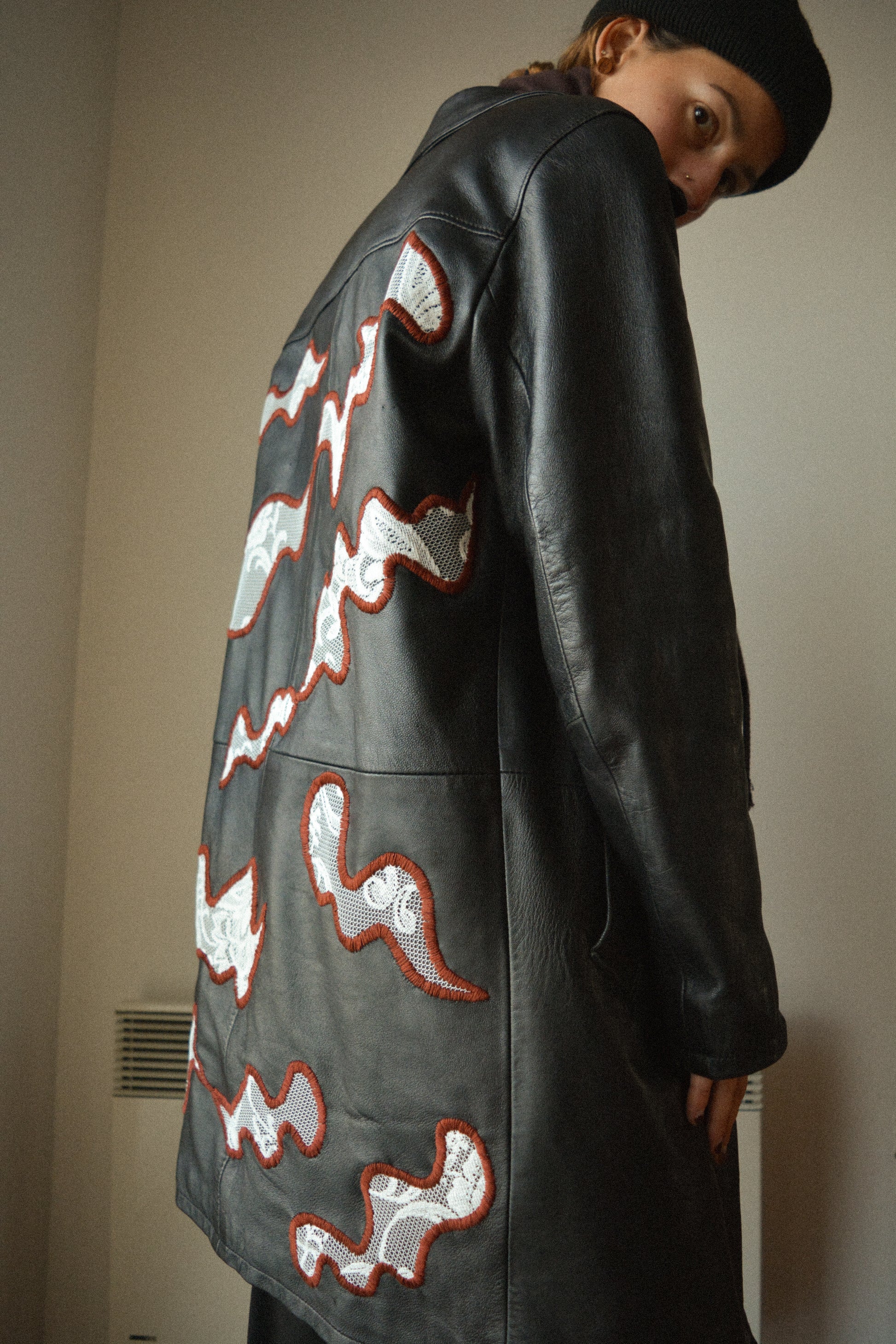 Manteau vintage en cuir noir de seconde main avec patchs en dentelle recyclé et broderie fait à la main au Québec par l’artiste Caroline Auger