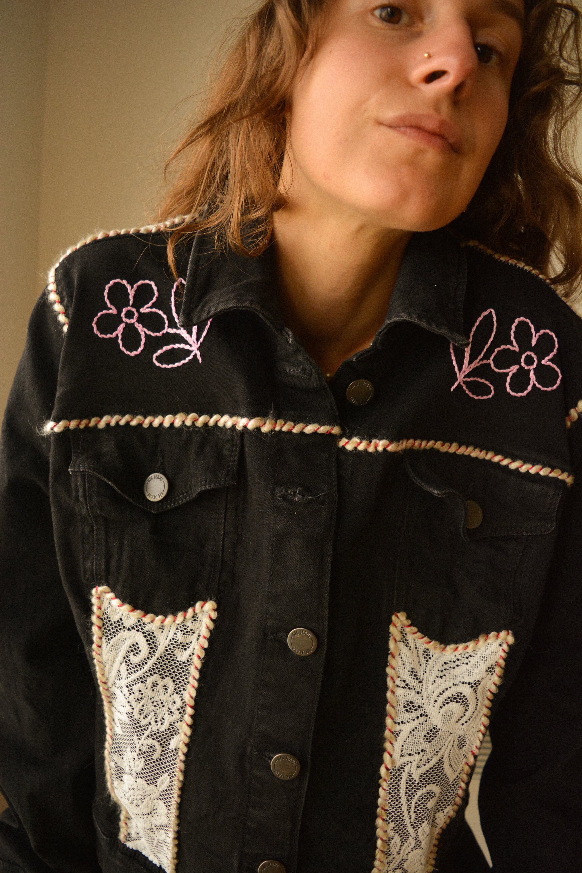 Veste en jeans noir vintage de seconde main à motifs de fleurs brodées, à laine brodés et à dentelle recyclée à la main au Québec par l’artiste et designer Caroline Auger