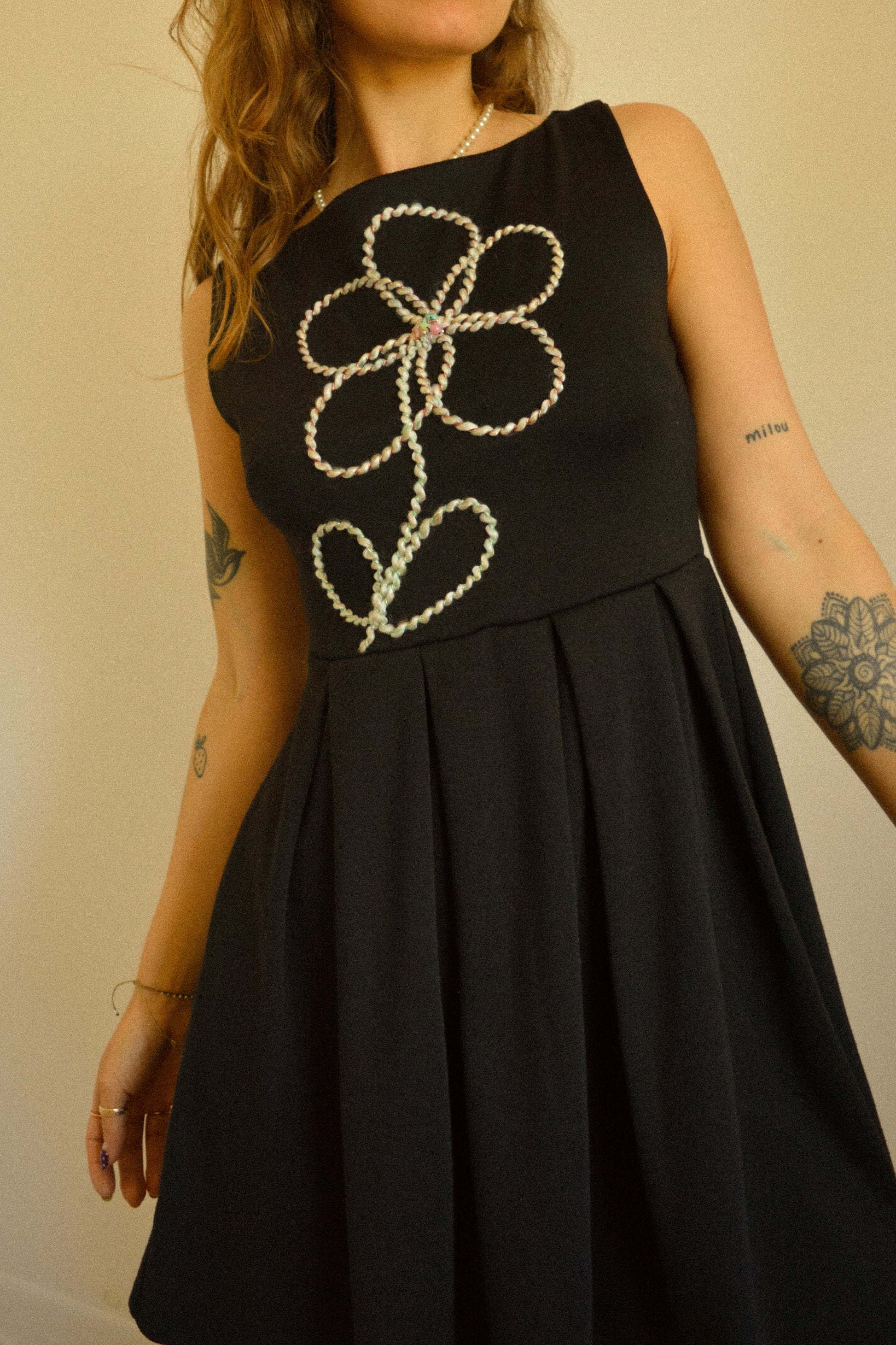 Robe noir de seconde main revalorisée par l'ajout d'un motif de fleur brodée à la main au Québec par l’artiste et designer Caroline Auger.