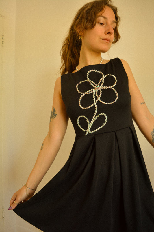 Robe noir de seconde main revalorisée par l'ajout d'un motif de fleur brodée à la main au Québec par l’artiste et designer Caroline Auger.