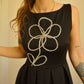 Robe noir de seconde main revalorisée par l'ajout d'un motif de fleur brodée à la main au Québec par l’artiste et designer Caroline Auger.