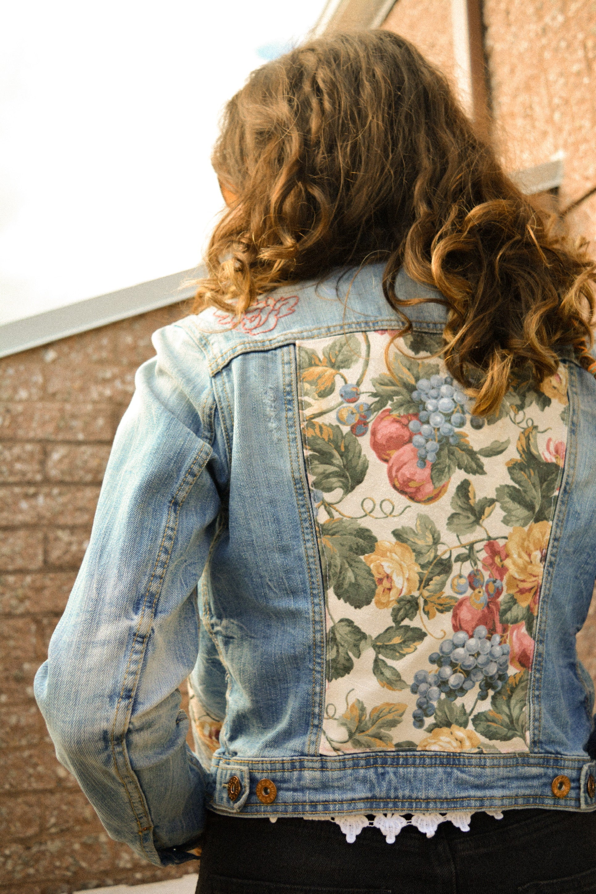 Veste de seconde main en jeans bleu à manches longues avec patch de tissu recyclé et motifs de fleurs brodées à la main au Québec par l’artiste Caroline Auger