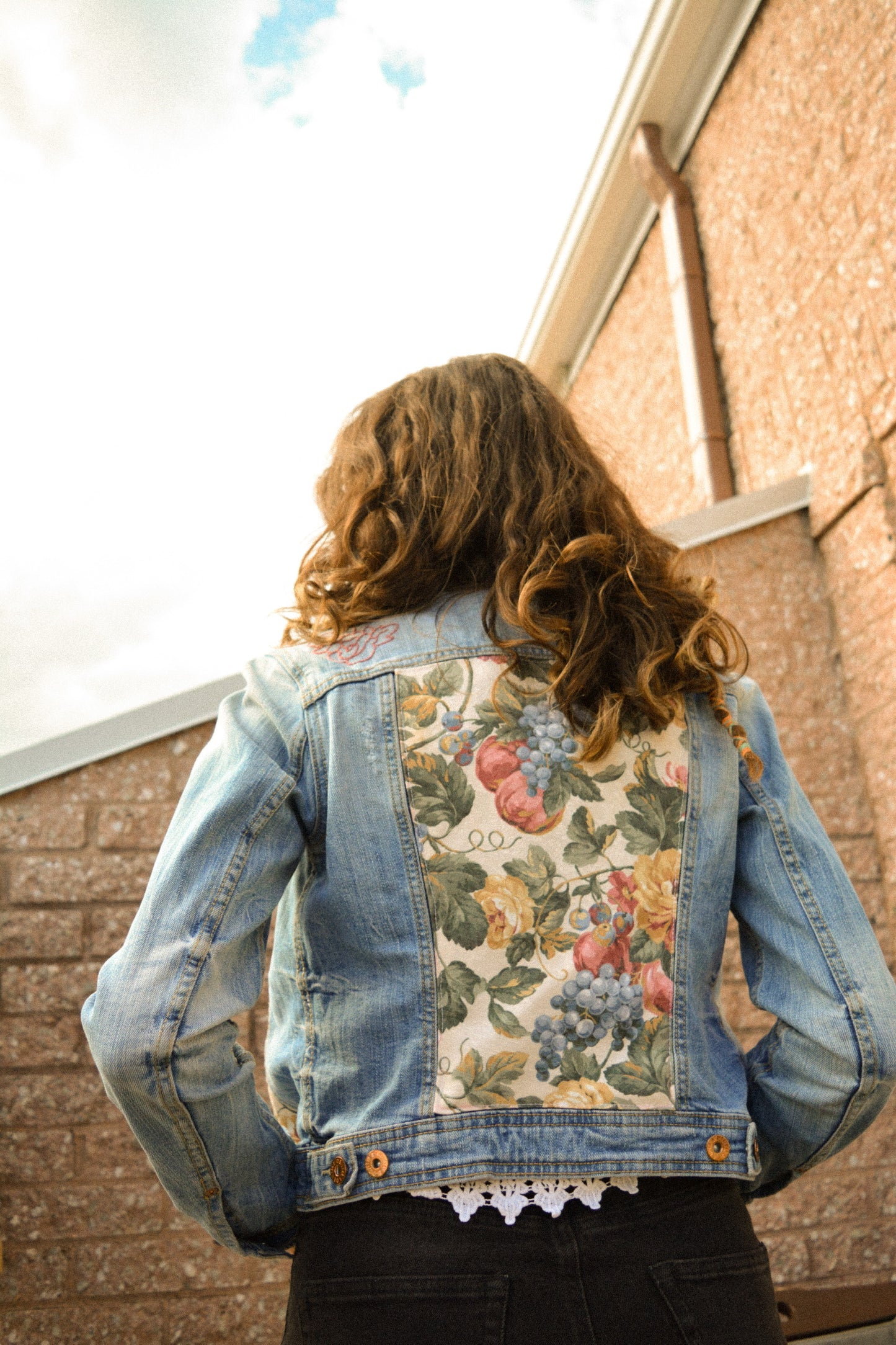 Veste de seconde main en jeans bleu à manches longues avec patch de tissu recyclé et motifs de fleurs brodées à la main au Québec par l’artiste Caroline Auger